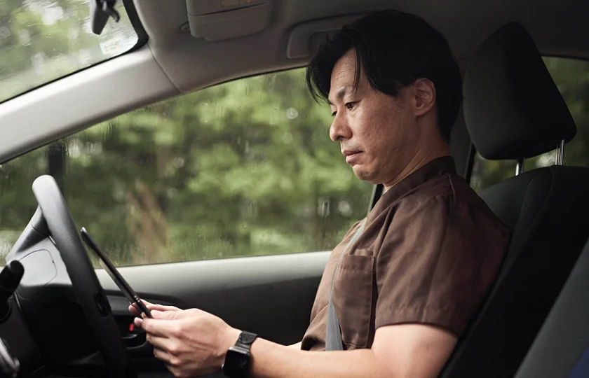 訪問先へ車で移動しながらタブレットを確認するふるねすのスタッフ